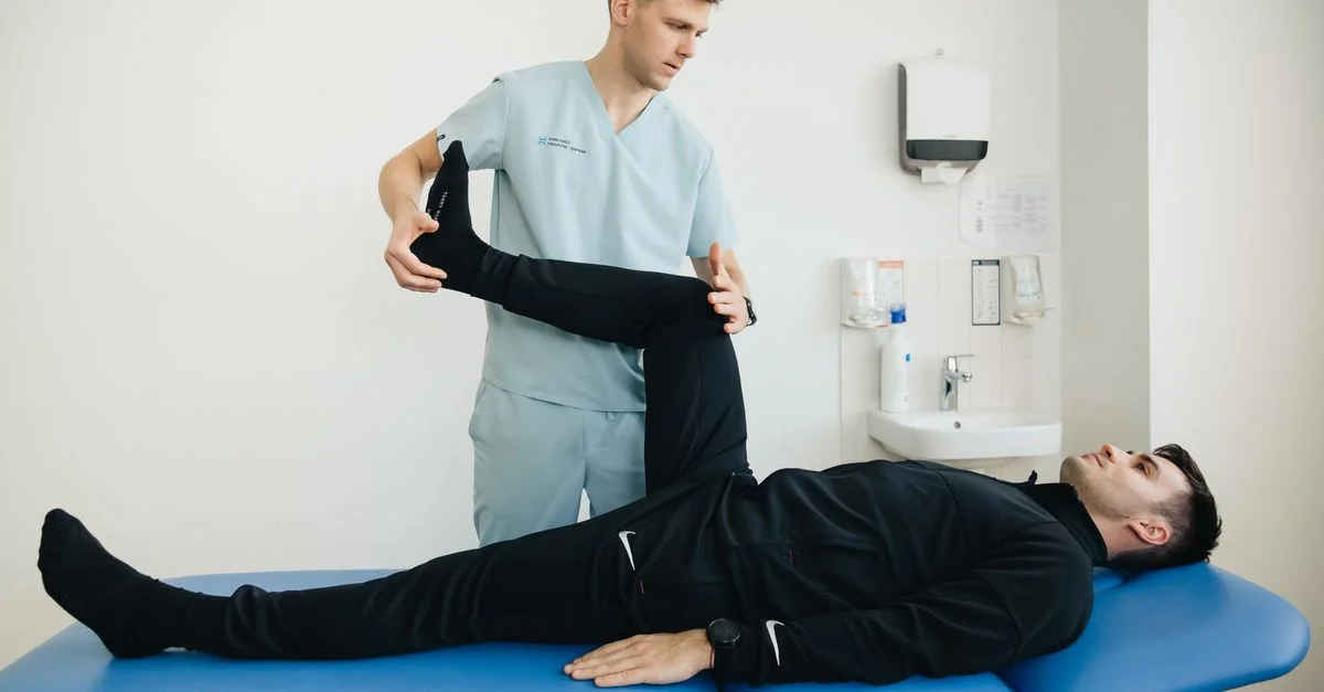 Un physiothérapeute aide un patient avec des exercices d'étirement des jambes sur une table de traitement.