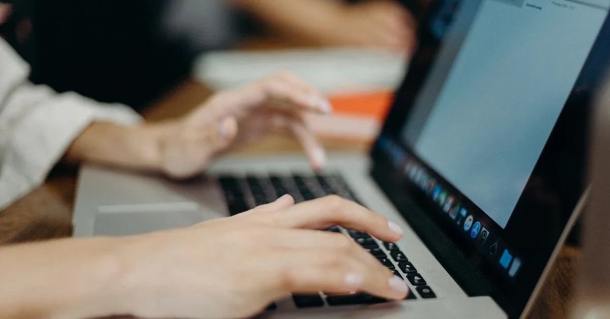 Personne tapant sur un ordinateur portable dans un bureau. Focus sur les mains et le clavier.