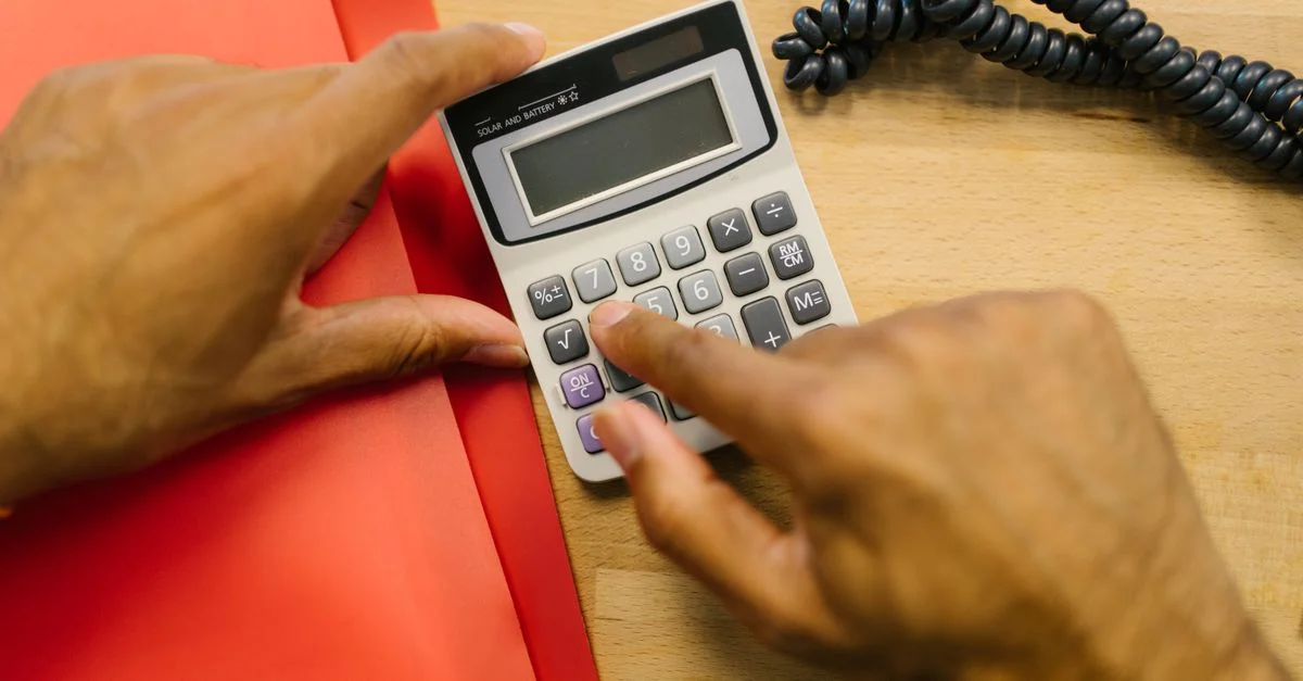 Gros plan sur des mains utilisant une calculatrice à un bureau dans un cadre de bureau.